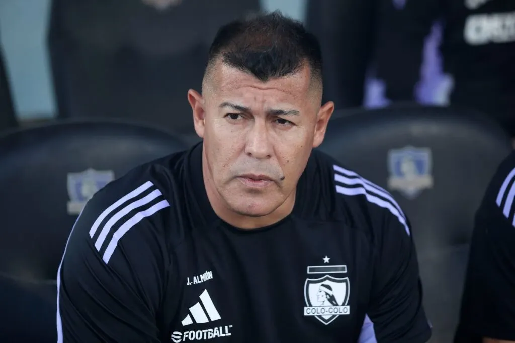 Jorge Almirón con indumentaria de Colo-Colo en un banco de suplentes.