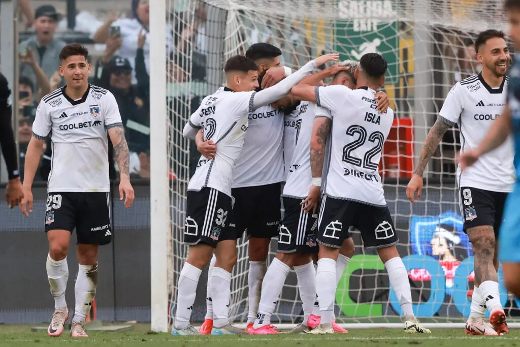 Jugadores de Colo-Colo abrazados celebrando un gol.