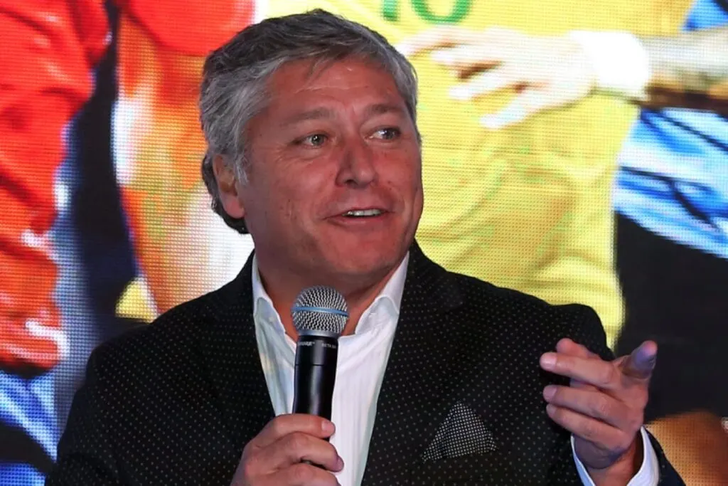 Primer plano a Patricio Yáñez sonriendo con un micrófono en la mano.