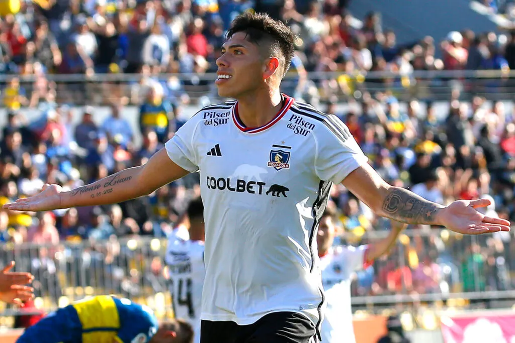 Carlos Palacios sonriendo con los brazos abiertos.