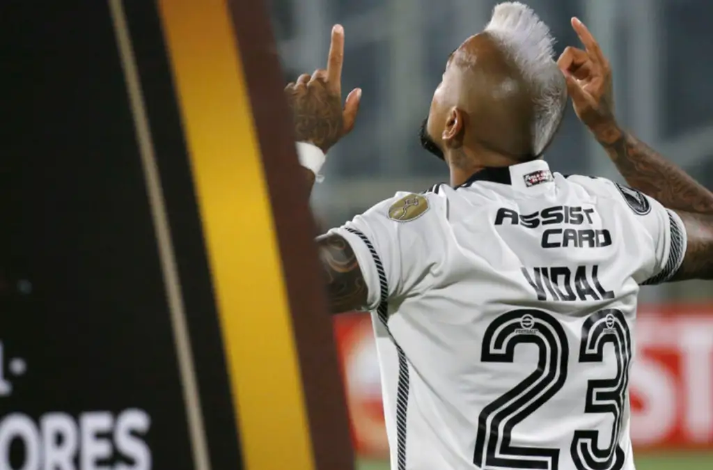 Arturo Vidal de espaldas y sus dos manos levantadas jugando por Colo-Colo.