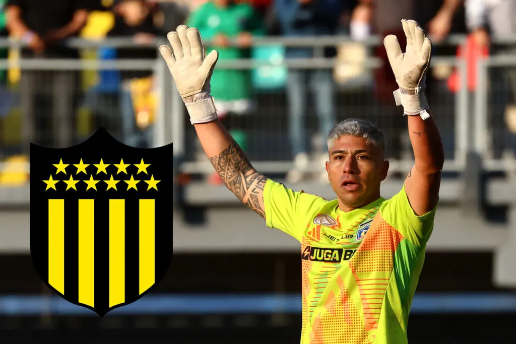 Brayan Cortés con las manos arriba junto al escudo de Peñarol.