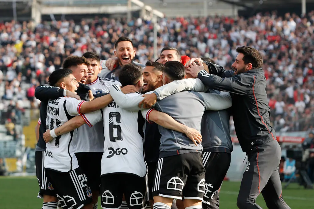 Jugadores de Colo-Colo abrazados celebrando un gol.