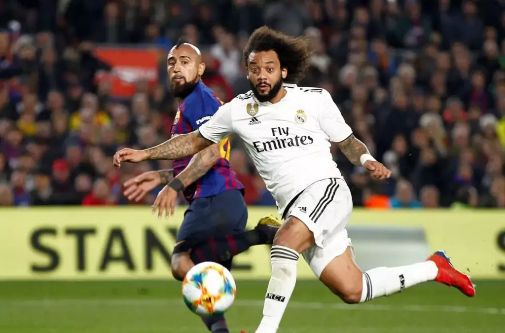 Arturo Vidal y Marcelo disputando un balón en el derbi entre Real Madrid y Barcelona en España.