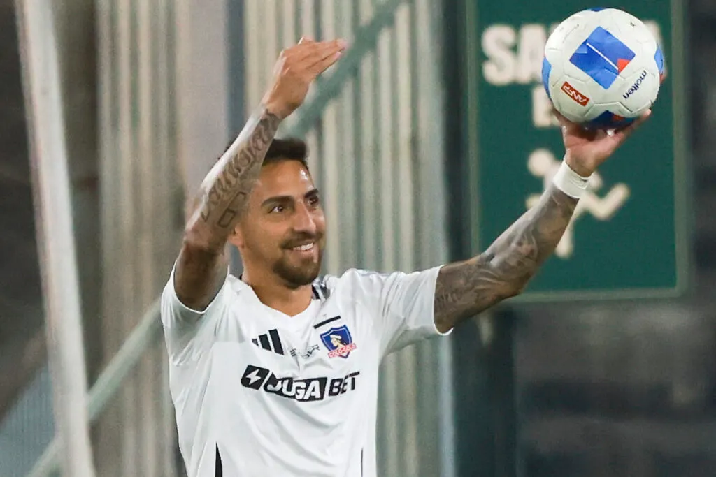 Primer plano de Javier Correa con camiseta de Colo-Colo y una pelota en su mano.