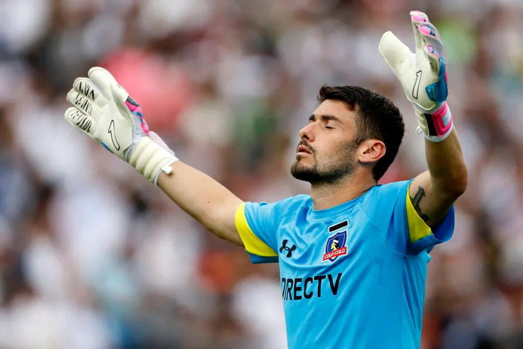 Paulo Garcés con las manos arriba y rezando en medio de un partido con la camiseta de Colo-Colo.